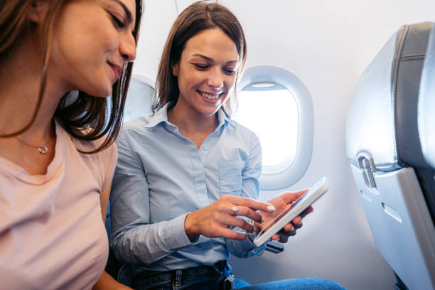 istock Two Young Female Friends Using Phone In An Airplane 2154835523