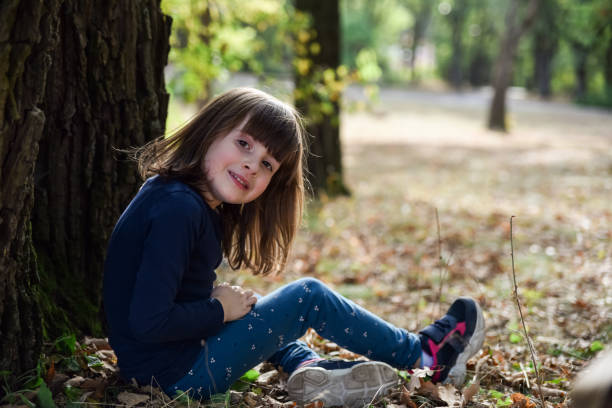 istock Happy girl sitting under a tree in park 2154836102