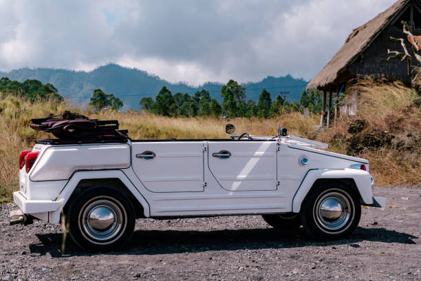 Beekbergen, The Netherlands - September 6, 2015: 1950s Volkswagen Samba or Sunroof Deluxe classic car. Two people are sitting inside the VW that is driving on a country road.