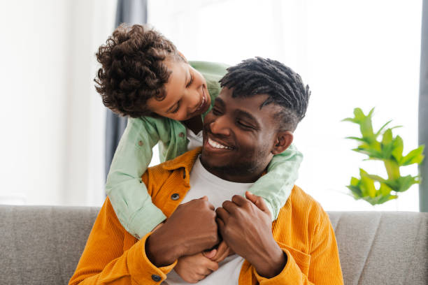 istock Smiling, attractive African American young father and little son hugging 2154836558