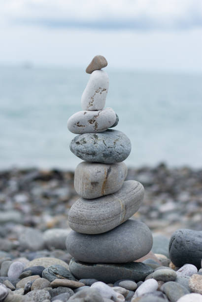 istock Balanced pebble pyramid silhouette on the beach with the ocean in the background 2154837606