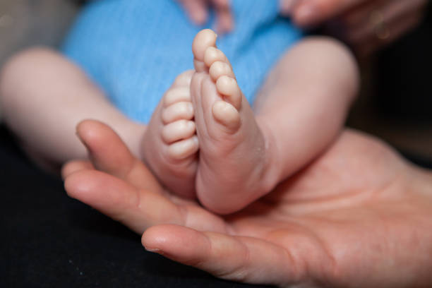 The tiny hands of a newborn baby held in the mother's hands with love and warmth.
