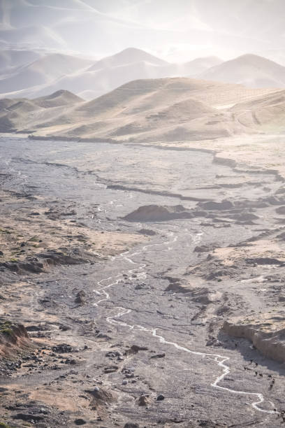 A small mountain river flows in a rocky valley from the mountains among stones in the evening at sunset in the mountains of Tajikistan