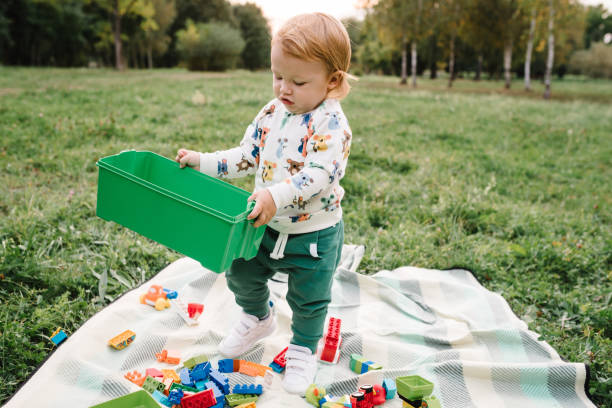 Two tiny workmen in front of plastic bucket and space with rake