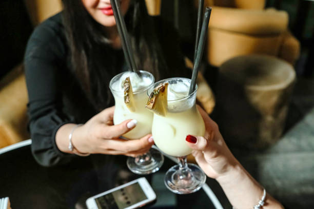 A couple of individuals smiling and holding drinks while surrounded by a vibrant atmosphere outdoors.