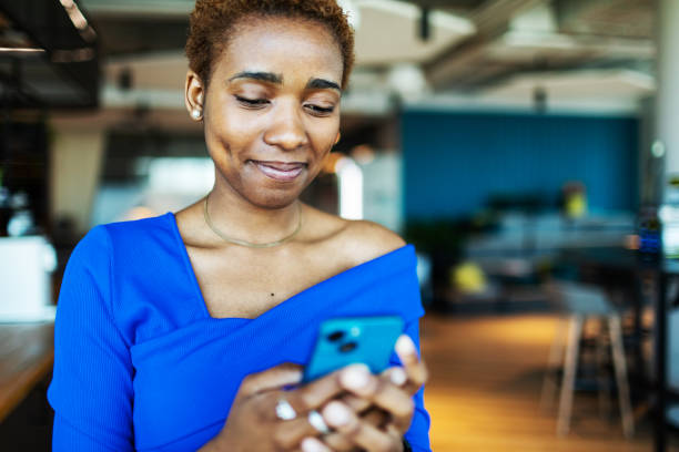 istock Young adult black woman using mobile for text messaging 2154846506