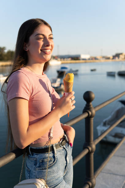 istock A woman is smiling and holding an ice cream cone. Vertical image. Vacations concept 2154847102