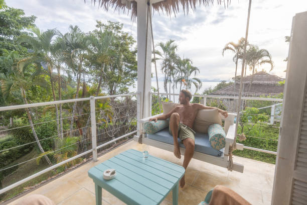 istock Man relaxing on balcony swing with tropical view 2154849049