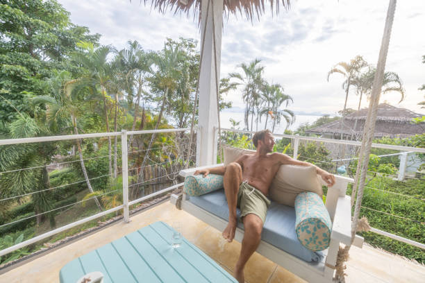 istock Man relaxing on balcony swing enjoying tropical view 2154849051