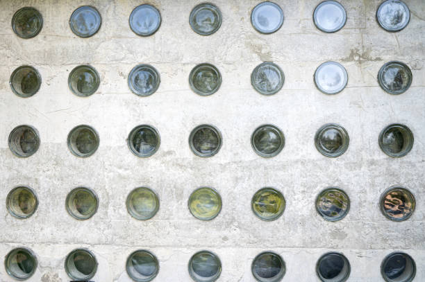 A close-up of a concrete wall with embedded round glass blocks