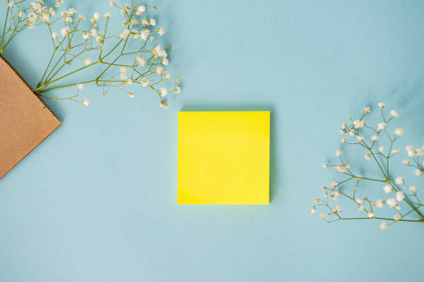 A clean square sheet on a blue table with white flowers, top view. Place for text