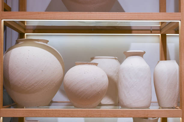 Beige vases of different sizes are on the shelf in the store