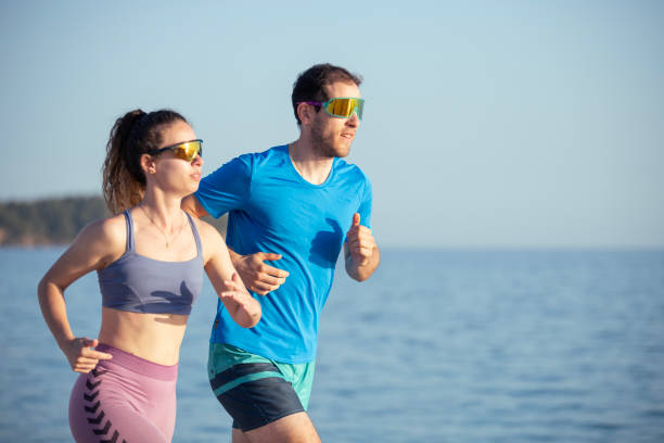 Young couple are jogging on the beach to maintain healthy and active lifestyle.