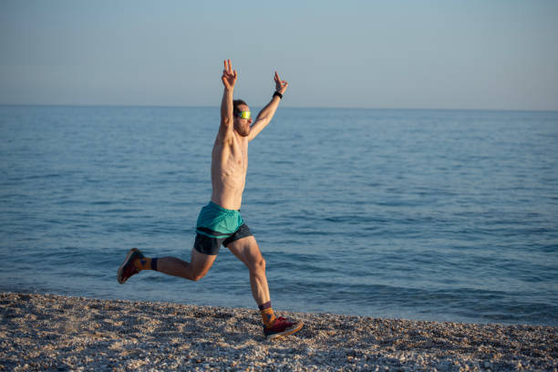 Healthy male runner during sunset on the beach doing a workout jog.