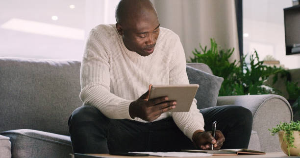 istock Remote work, tablet and black man with notes in home for planning, website and writing ideas. Startup career, consulting job and person on digital tech for internet, research and working on project 2154852996