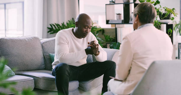istock Therapy, psychology and black man consulting therapist on a sofa for help with depression, anxiety or ptsd trauma. Counseling, mind or African patient with psychologist for empathy, support or stress 2154853018