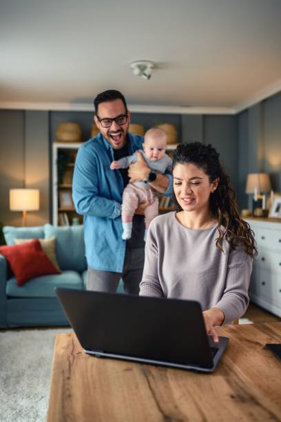 istock Family with a baby at home, mom using a laptop. 2154856139