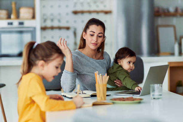 istock A single mother taking care of her children while working from home and reading her notes 2154862297