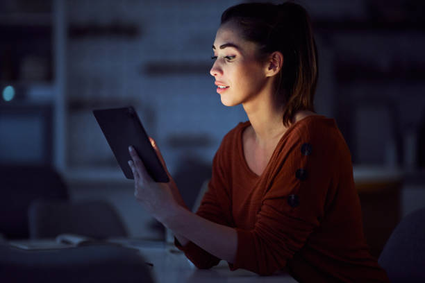 istock A beautiful young adult woman using her tablet while working late at night 2154862959