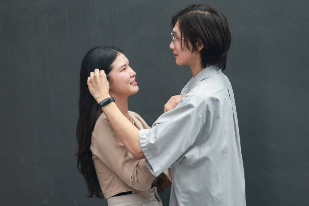 Asian lovers engage in playful interactions outdoors. Their eyes meet with affectionate gaze, radiating love and tenderness. Laughing and sharing intimate moments filled with warmth and playfulness.