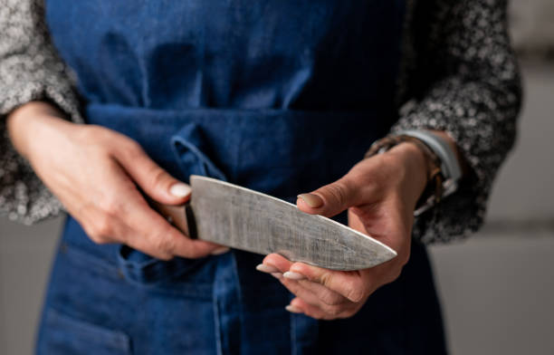 istock Woman Sharpens Knives In Kitchen Apron, Close Up 2154866865