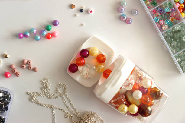 Colorful beads, letter beads, threads and other jewelry making supplies on white background. Making friendship bracelets concept. Flat lay.