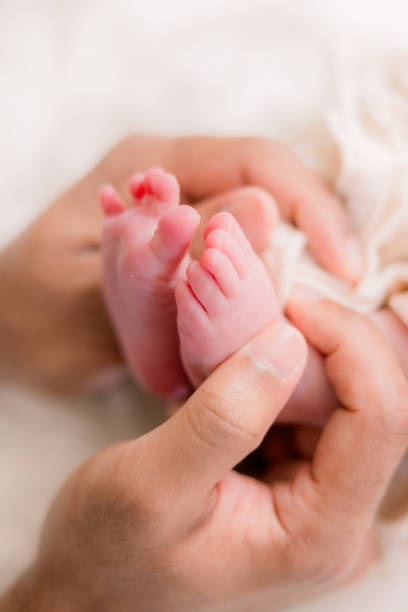 istock A father cradles his newborn baby's tiny feet in his hands. 2154877926