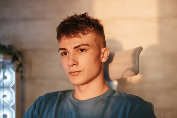 Portrait of a teenage boy sitting by the computer in a comfortable white gamer chair