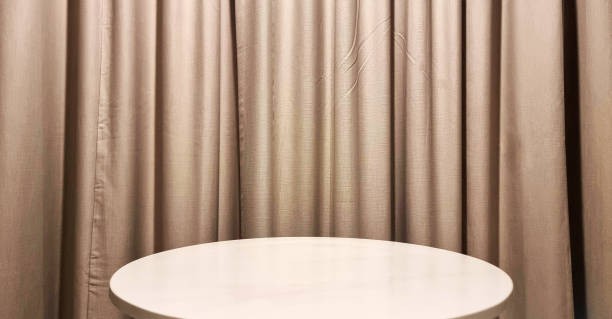 istock real empty round marble table with gold curtain background used for premium, luxury, deluxe concept. podium under spot light for with beige wavy drapery in background. 2154894344