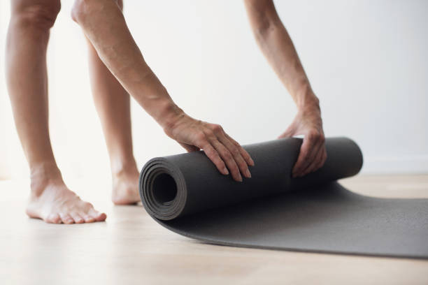 istock Woman rolling up exercise mat and preparing doing yoga or workout 2154894768