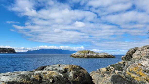 istock Hidden cove: idyllic beach and a rocky islet framed by rugged cliffsand rocks on a sunny day with Clouds in the blue sky 2154895456