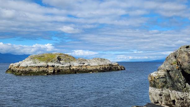 istock Hidden cove: idyllic beach and a rocky islet framed by rugged cliffsand rocks on a sunny day with Clouds in the blue sky 2154895466