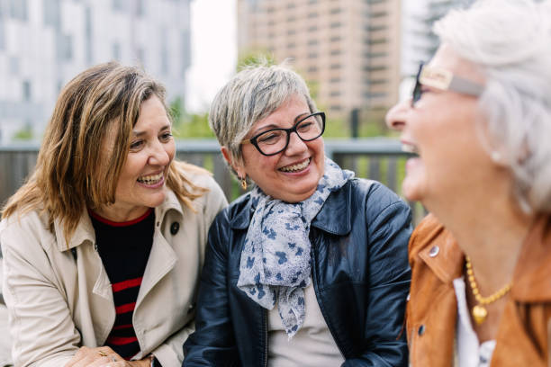 istock Three mature retired women laughing while talking sitting outside. 2154901770