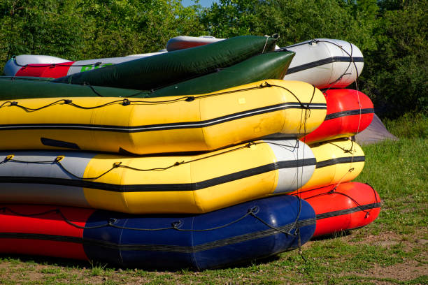 istock A stack of colorful canoes on grass, with trees in the background. 2154903917
