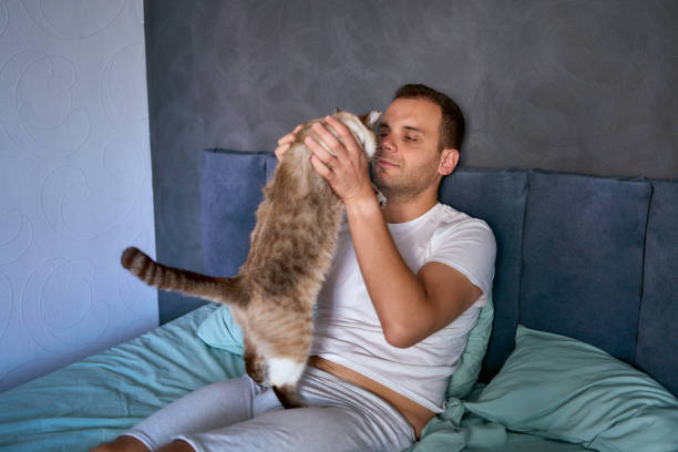 istock a  young man pet a cat in bed, morning routine 2154906904