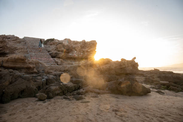 Young woman walks up stone steps in evening light