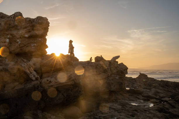 Young woman explores rocky shoreline at sunset