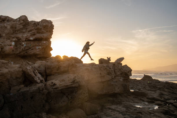 istock Young woman jumps between stones on beach 2154911153