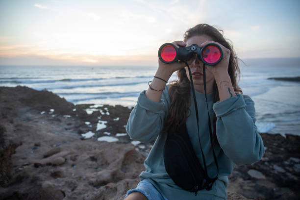 istock Young uses binoculars on rocky shoreline 2154911407