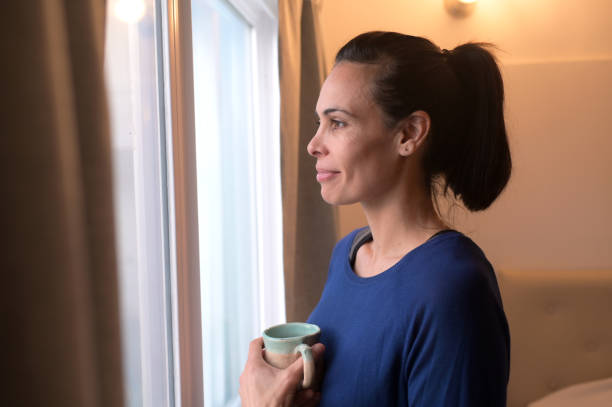 istock relaxed woman looking out the window 2154911844