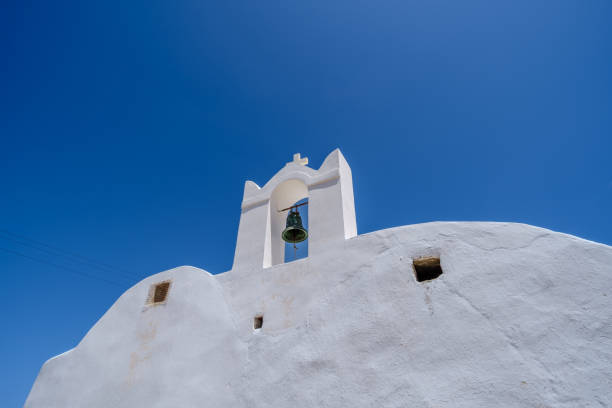 View of a beautiful whitewashed orthodox Chapel with a bell and a cross on the top in Ios Greece