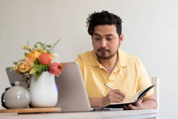 istock Student writting in his notebook and looking his laptop 2154912368