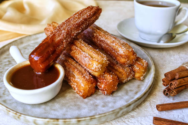 Churros with hot chocolate sauce, sugar and cinnamon .