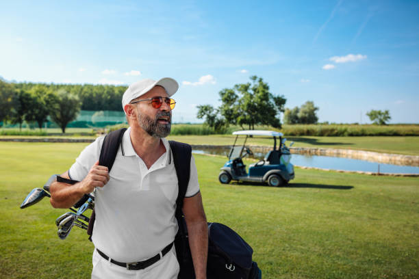 istock Handsome aged golfer walking down the golf course, smiling 2154914545