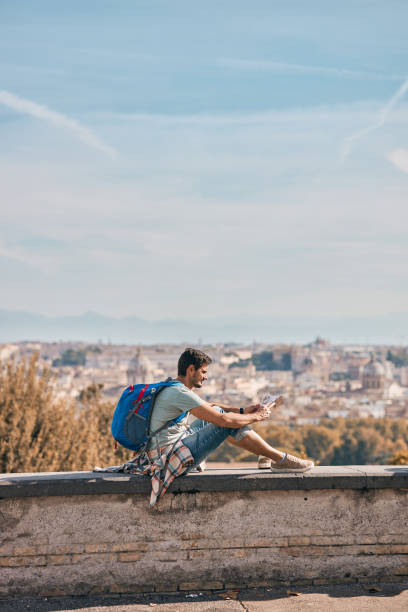 istock Young male tourist reading a map while exploring big city 2154915790