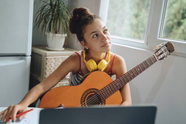 istock Thoughtful girl with guitar at computer 2154916130