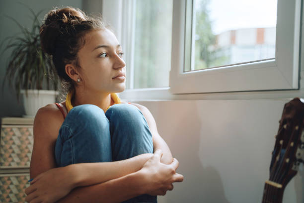 istock Pensive young lady near the window 2154916144