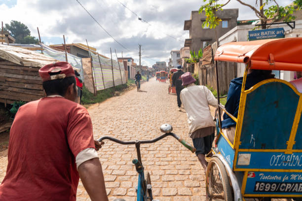 Antsirabe, Madagascar - View on street from a rickshaw on cobble stone street in Antsirabe, the third biggest town in Madagascar. Small group of people around on sunny day.  Antsirabe.