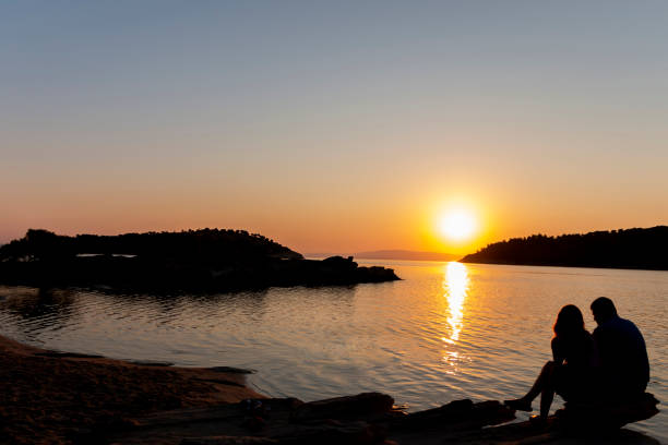 istock As the sun dips below the horizon, casting a warm orange glow across the sky, a striking silhouette emerges on the beach. The serene scene captures the tranquil beauty of nature and the intimacy of the moment that the couple shares. 2154919777