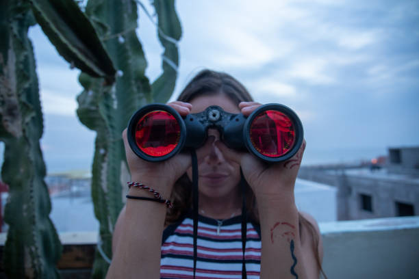 Young woman using binoculars on rooftop terrace